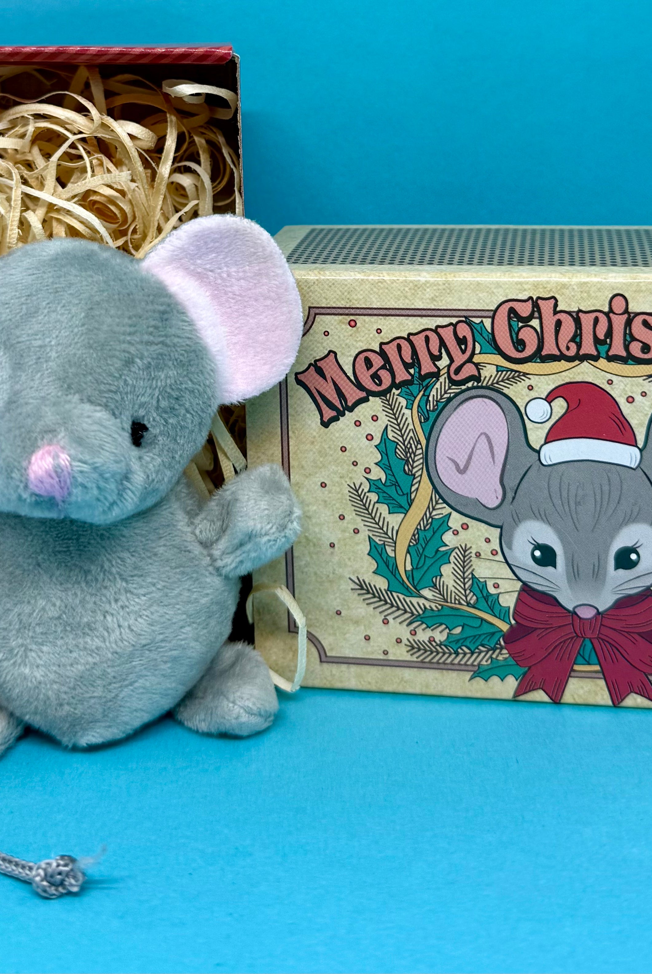 Plush christmas mouse toy with a decorative box featuring 'Merry Christmouse' text on a blue background.