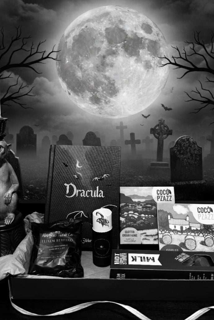 Spooky Halloween-themed gift set from bluebells and thyme with 'Dracula' book, candy, and decorative items against a moonlit cemetery background.