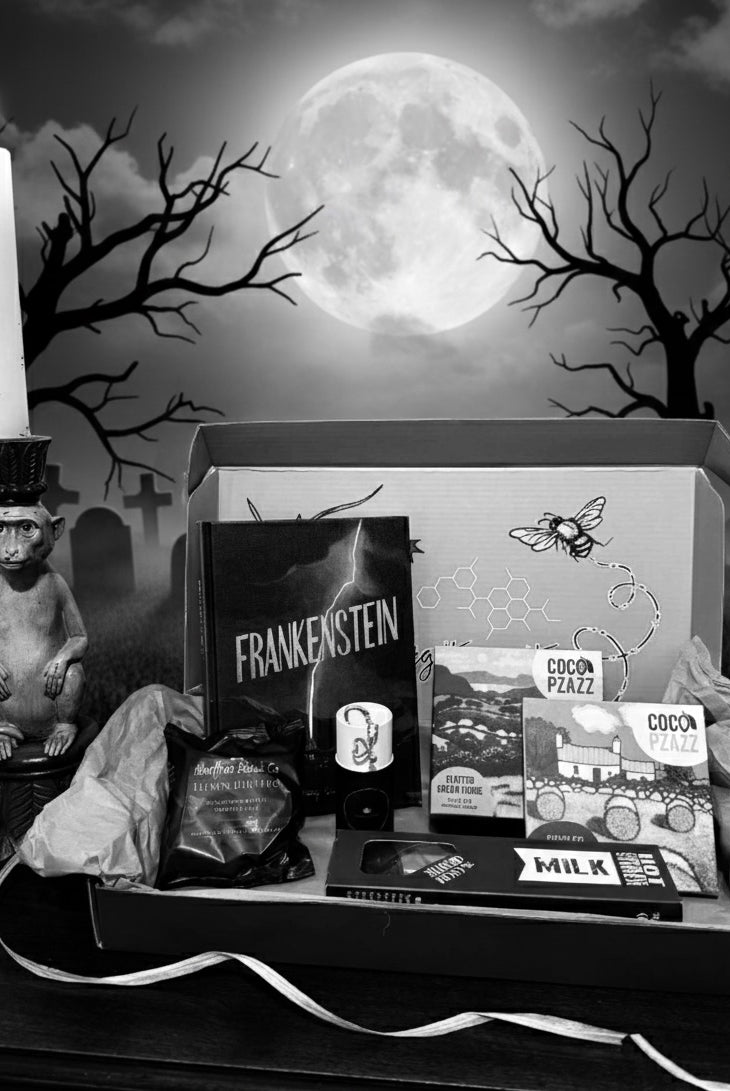 Halloween-themed gift box from bluebells and thyme with Frankenstein book and a candle in front of a moonlit sky.