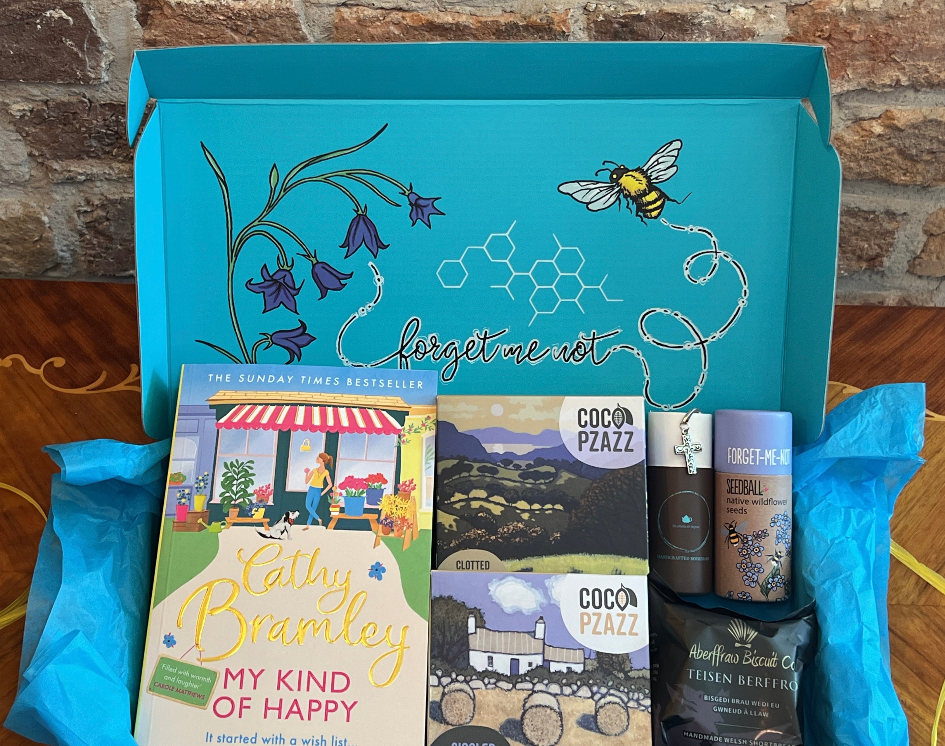 Letterbox Gift box from bluebells and thyme with books, handcrafted bookmark and artisan food and on a wooden surface