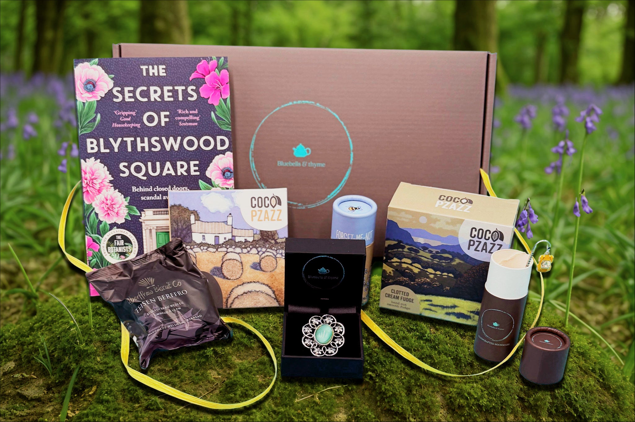 Summer meadow setting for Bluebells & Thyme 'Just Because' gift box with brooch, book, treats.
