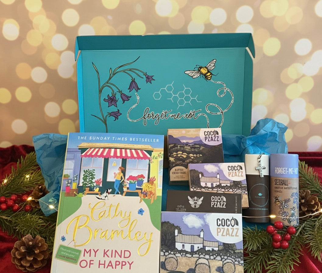 Christmas Gift box from bluebells and thyme with books, stationery items, and a small decorative sign on a festive background.