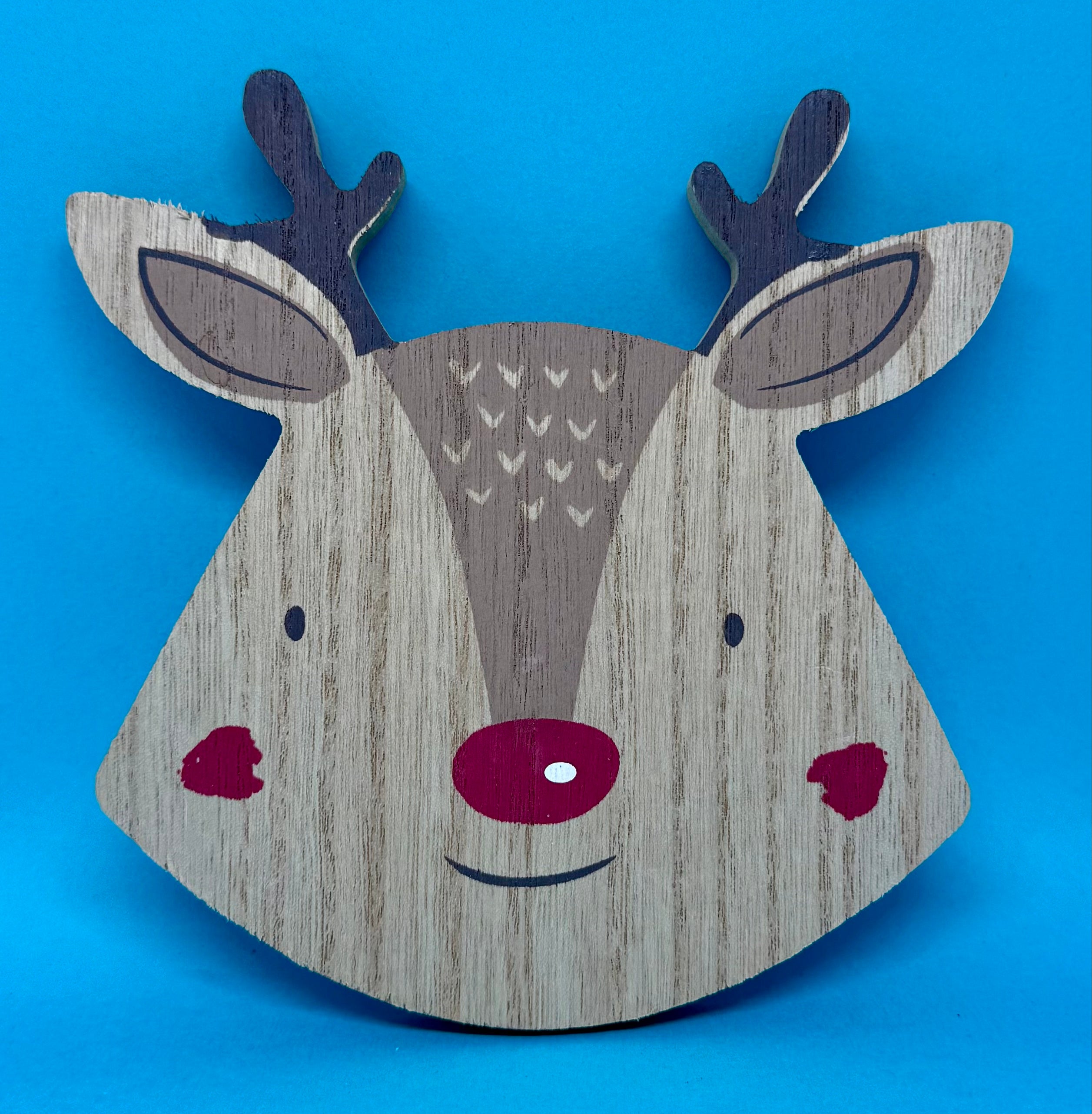 Wooden reindeer head coaster decoration on a blue background